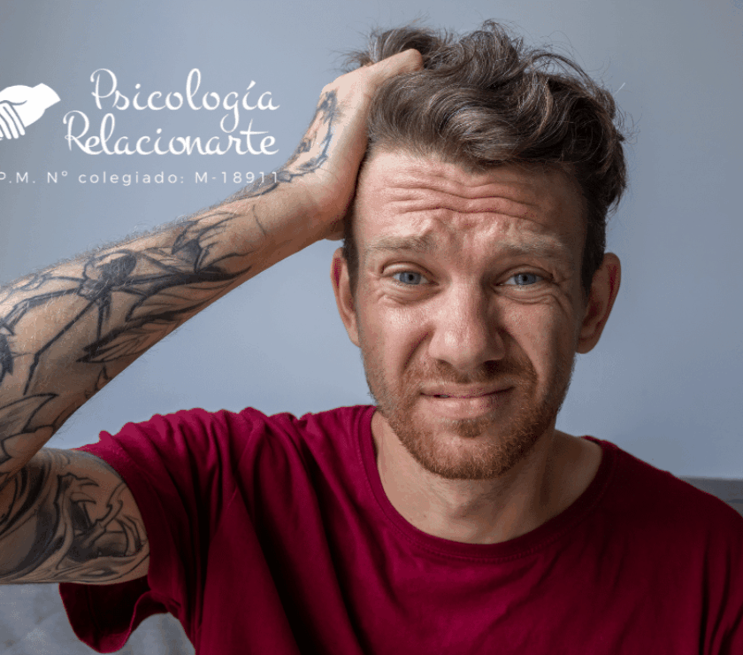 Un hombre con camiseta roja y tatuajes en el brazo llevándose la mano a la cabeza por un Un hombre con camiseta roja y tatuajes en el brazo llevándose la mano a la cabezaUn hombre con camiseta roja y tatuajes en el brazo llevándose la mano a la cabeza por un diagnóstico tardío de tdah en adultos
