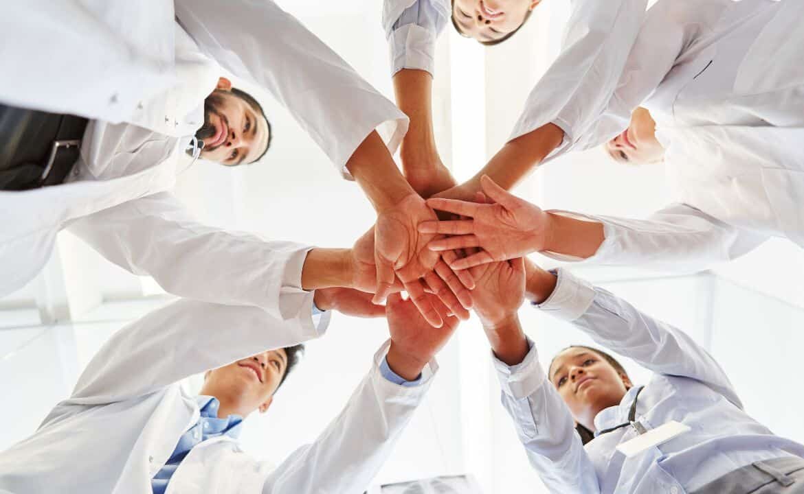grupo de profesionales sanitarios con las manos unidas en cooperación y compasión durante el coronavirus