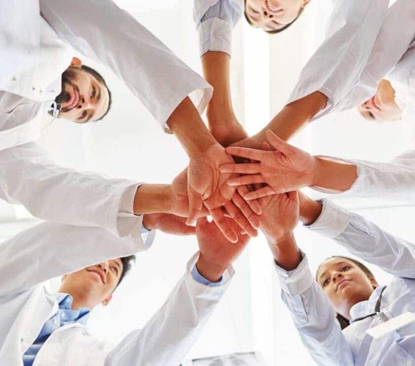 grupo de profesionales sanitarios con las manos unidas en cooperación y compasión durante el coronavirus