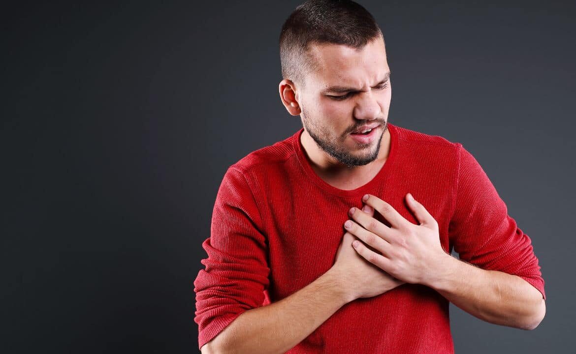 Hombre joven llevándose las manos al pecho temiendo un infarto por ansiedad