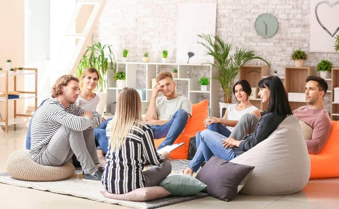 grupo de jóvenes sentados en cojines en círculo en sesión de terapia gestalt aplicando técnicas para su bienestar