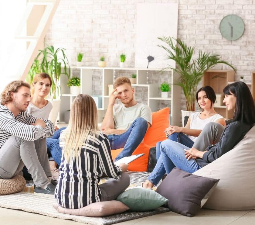 grupo de jóvenes sentados en cojines en círculo en sesión de terapia gestalt aplicando técnicas para su bienestar