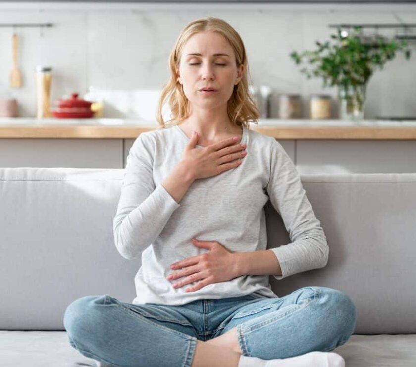 Mujer sentada en sofá concentrada practicando técnicas de respiración para la ansiedad