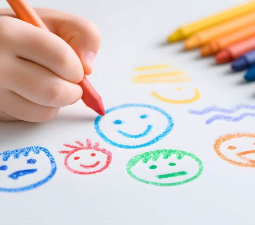 mano de niño dibujando con pinturas de colores caras para la educación emocional