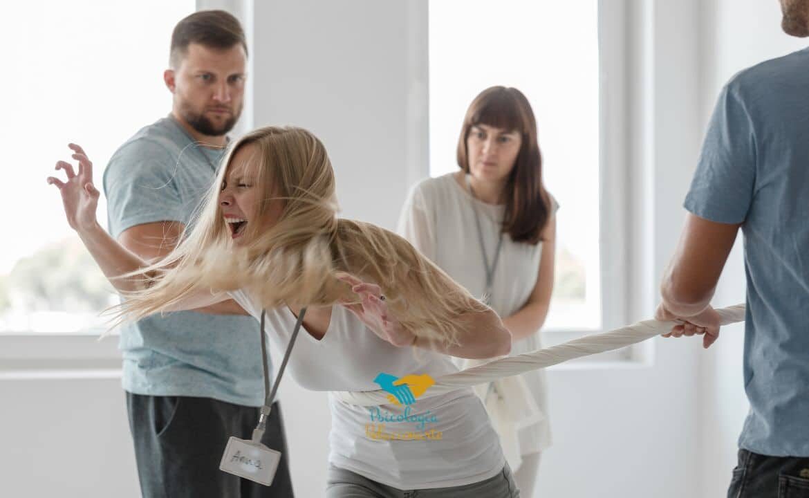 Mujer encolerizada rodeada de personas que intentan sujetarla para enseñarla el manejo de la ira