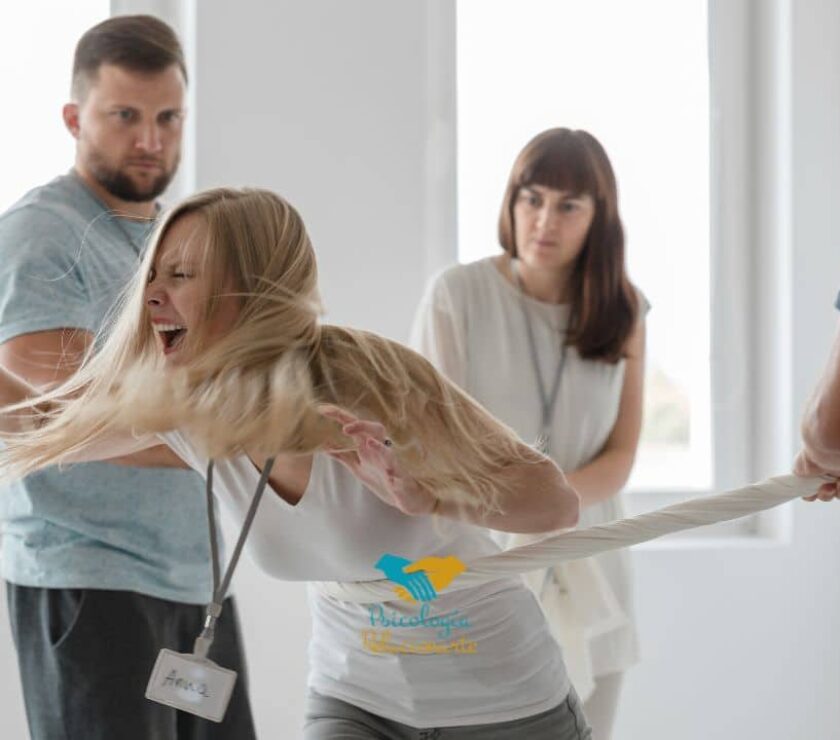 Mujer encolerizada rodeada de personas que intentan sujetarla para enseñarla el manejo de la ira