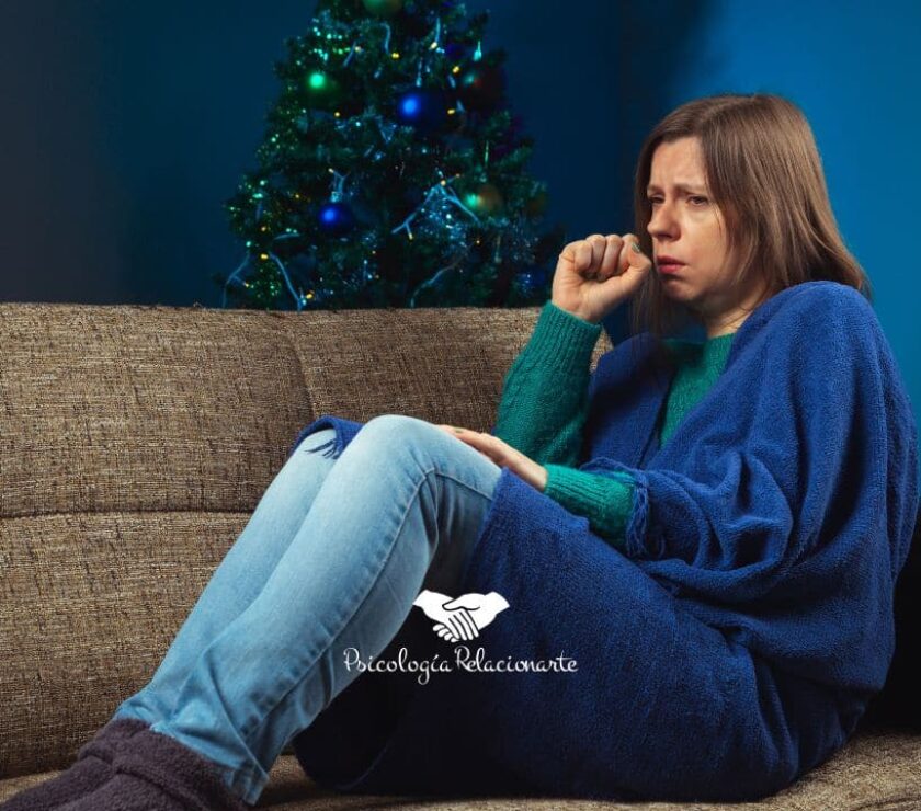 Mujer recogida en un sofá abrigada con una manta intentando manejar el estrés de las fiestas.
