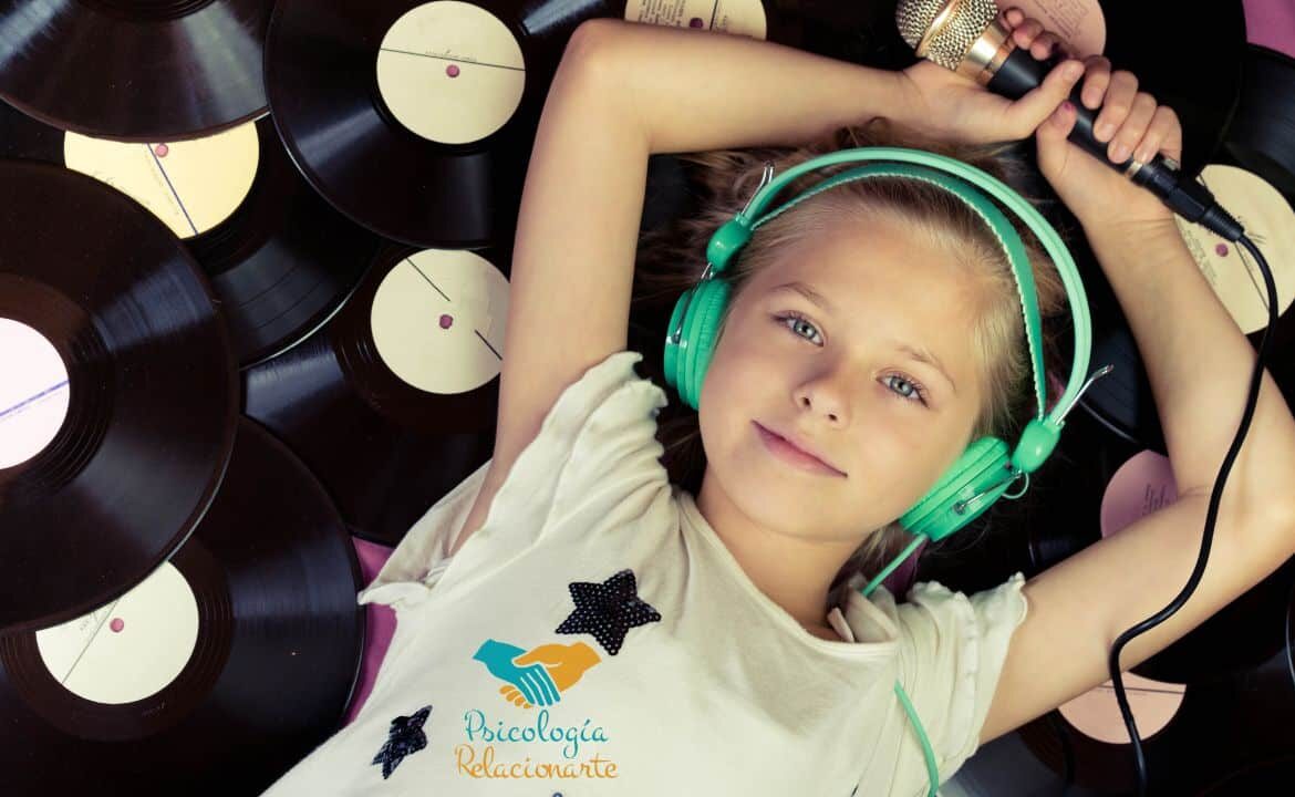 Niña con auriculares y micrófono recostada sobre un lecho de vinilos disfrutando de los beneficios de la música.
