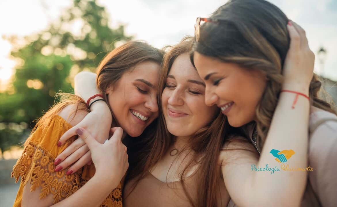 Tres chicasjuntando sus cabezas juntas mientras sonríen representando el valor de la amistad