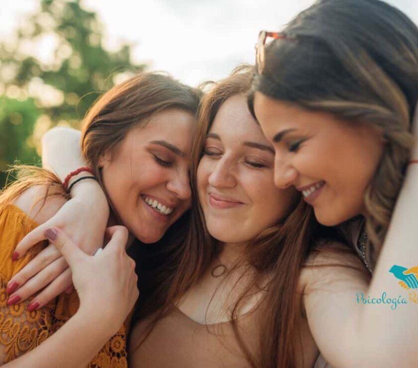 Tres chicasjuntando sus cabezas juntas mientras sonríen representando el valor de la amistad